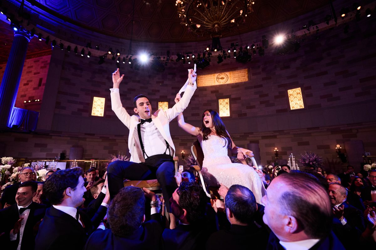 Couple lifted during hora at wedding reception
