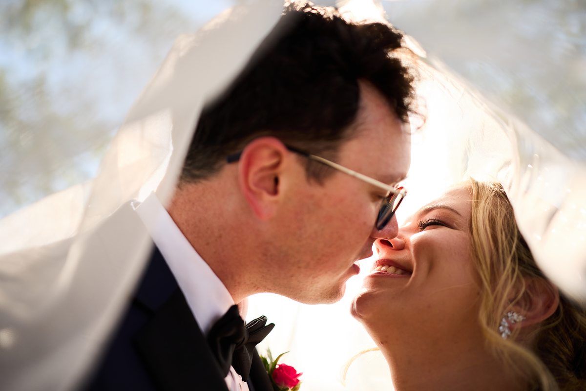 Bride and groom kissing under veil