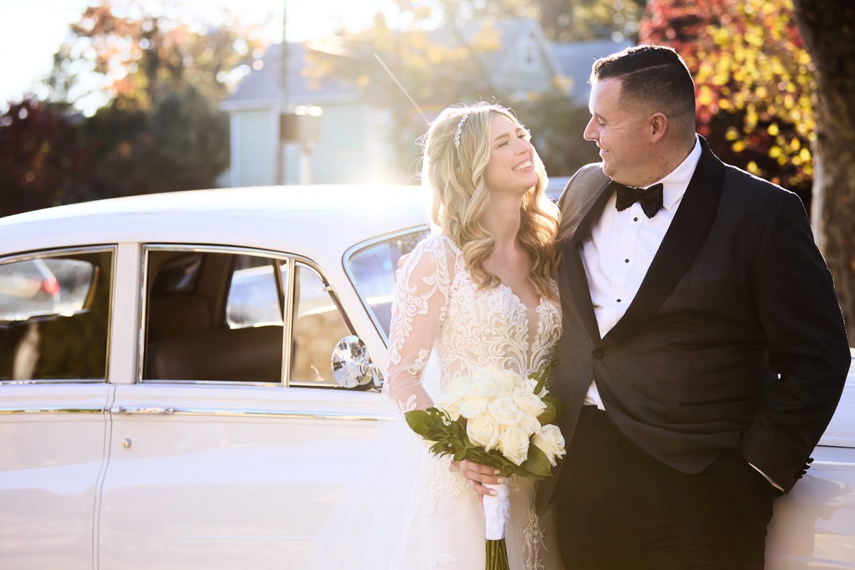 Couple by vintage car at golden hour